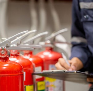 a man writing on a clipboard next to fire extinguishers